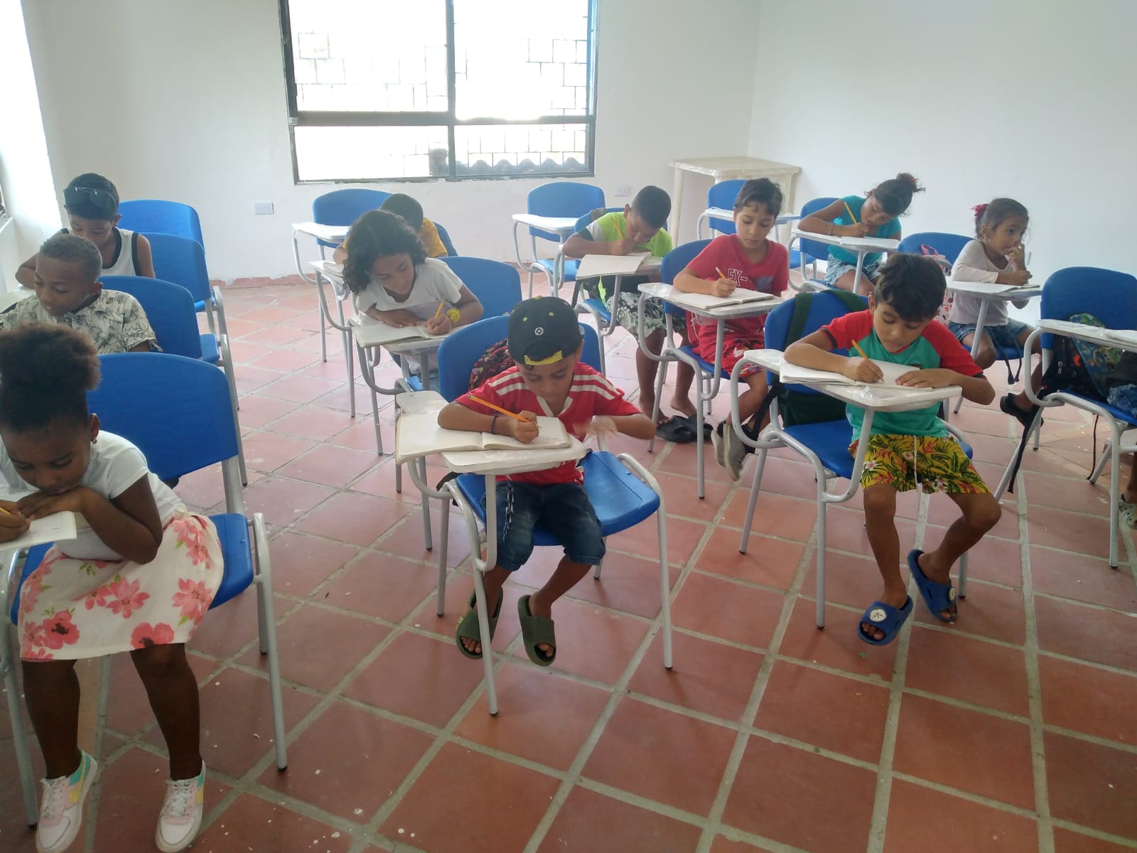 enfant en salle de classe qui ecrit dans un cahier